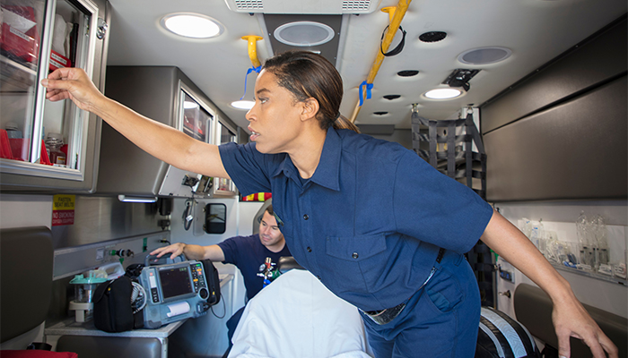 Female EMT reaches for medical equipment