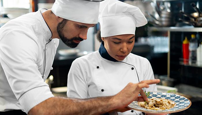 Professional chefs add finishing touches to plate before serving