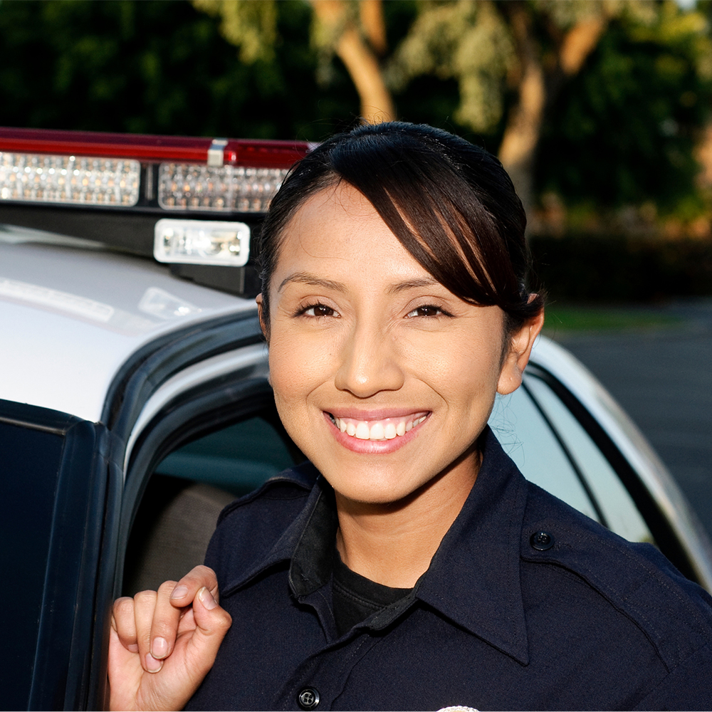 Law Enforcement Academy student stands next to police car