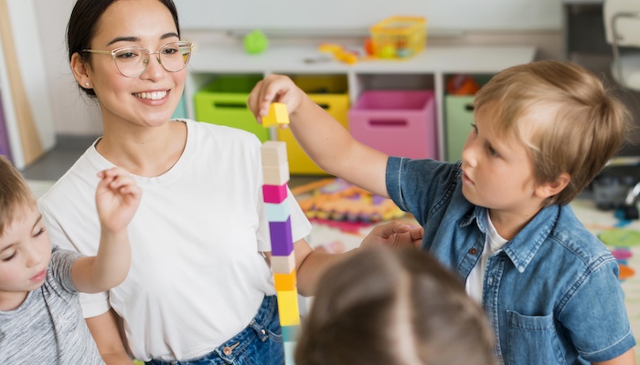 ECE Teacher Working with Young Children Stacking Blocks