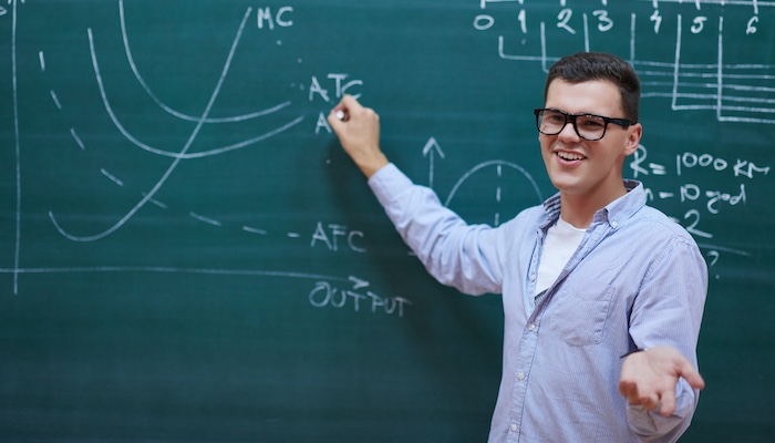 Physics Student Writing Formula on Chalkboard