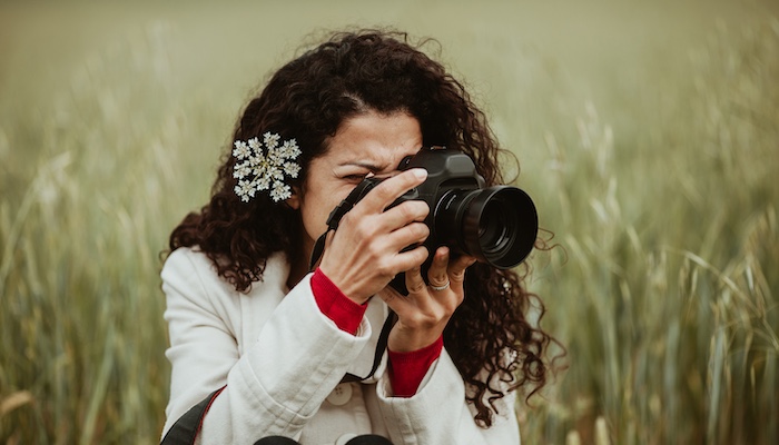 Woman Looking Through Camera Viewfinder Photographing Scenery in Field