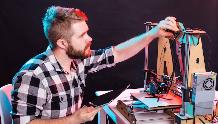 Artist Adjusting 3D Printer and Holding iPad