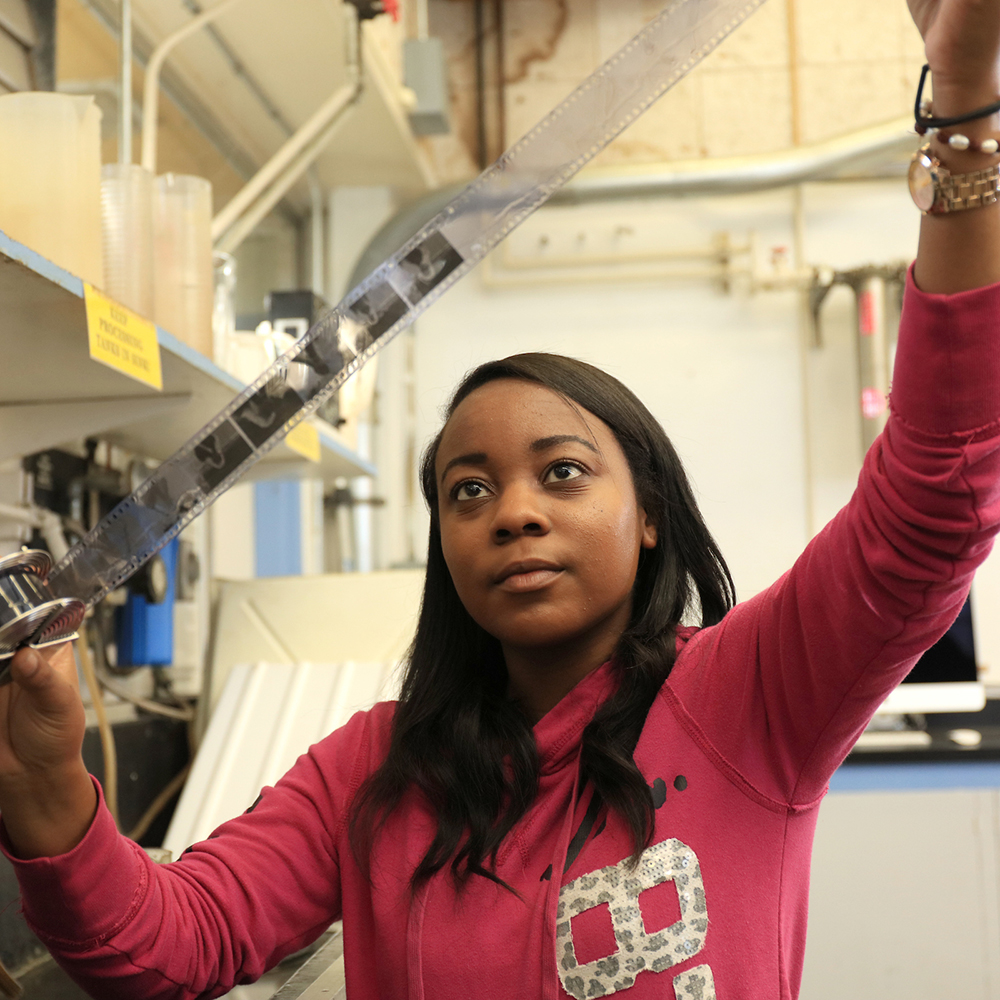 MPC Photography student examines negatives prior to printing during photography class