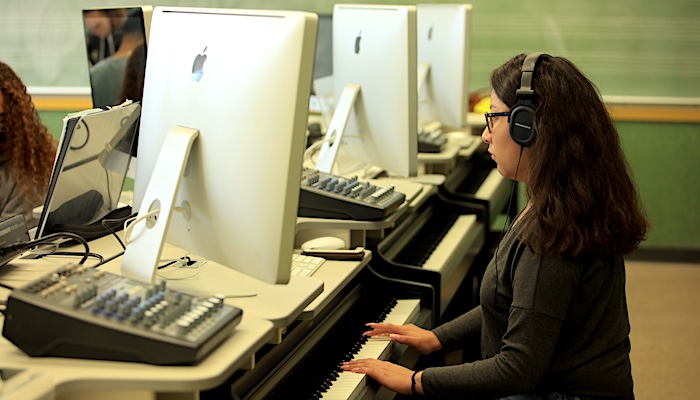 Music Student In Class with Headphones on Playing Piano