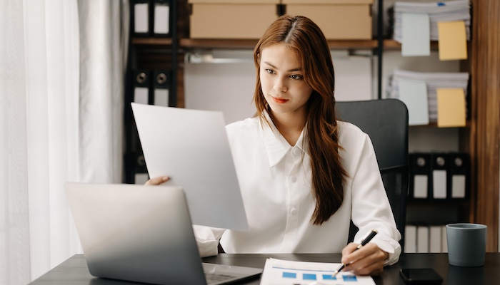 Person Working in Office Looking at Papers and Writing