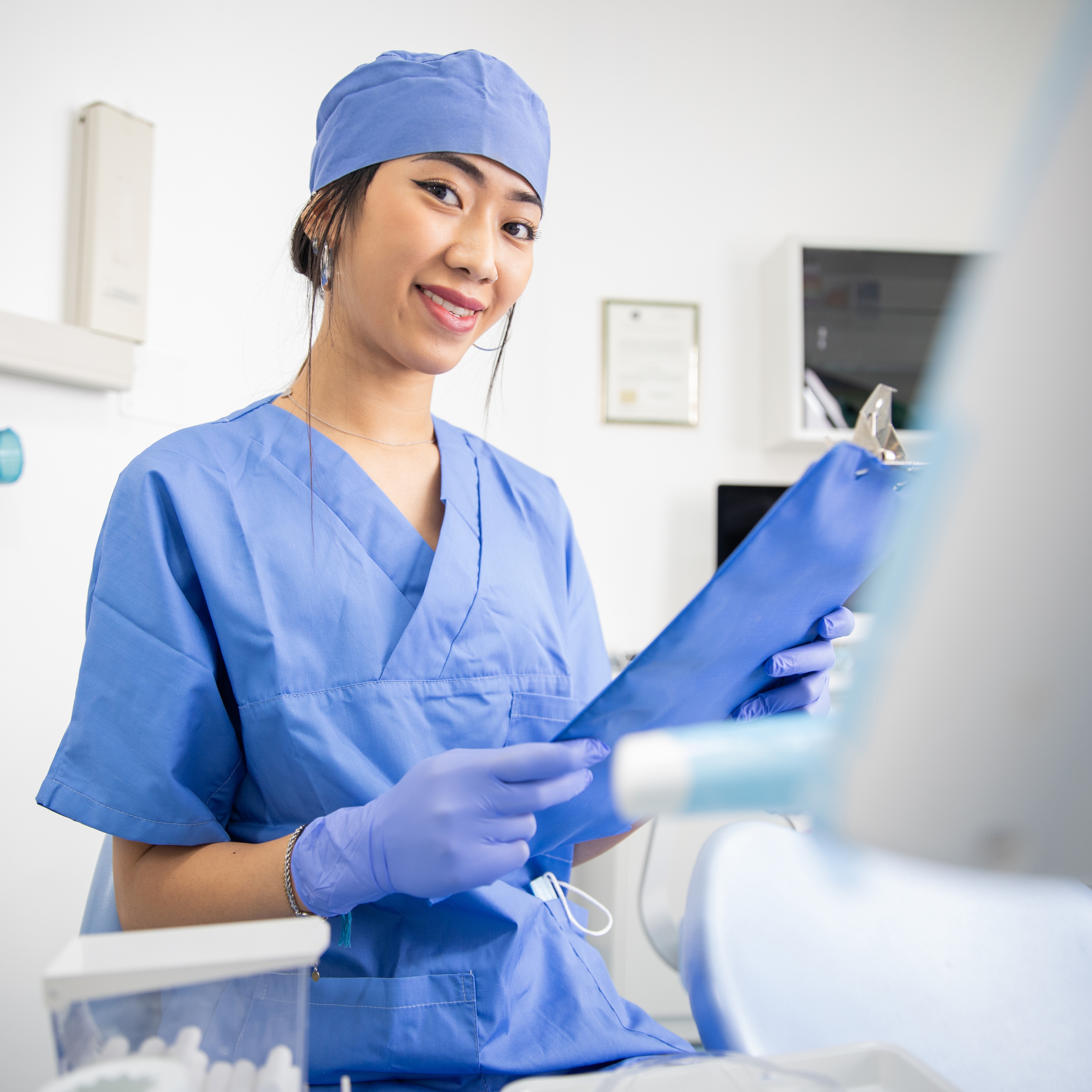 Dental Assistant Working in Office Holding Clipboard