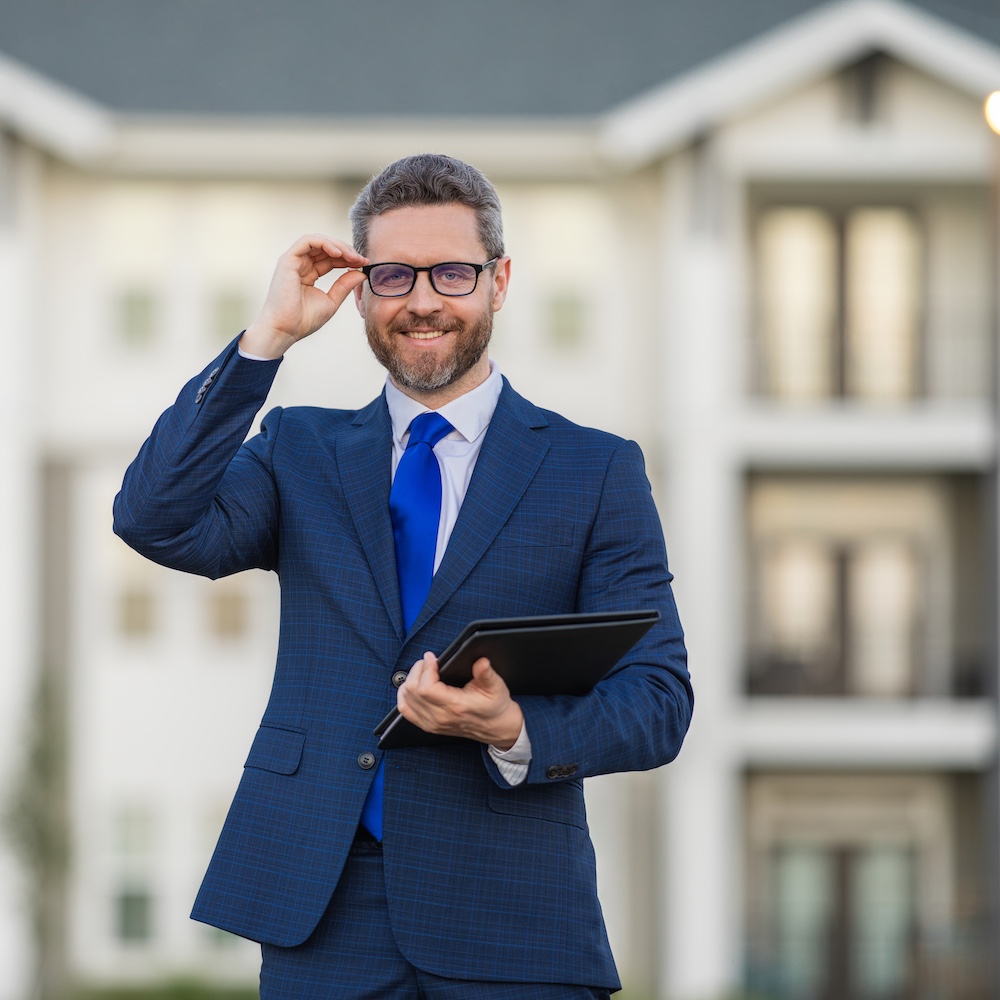 Real Estate Agent Smiling in Front of House