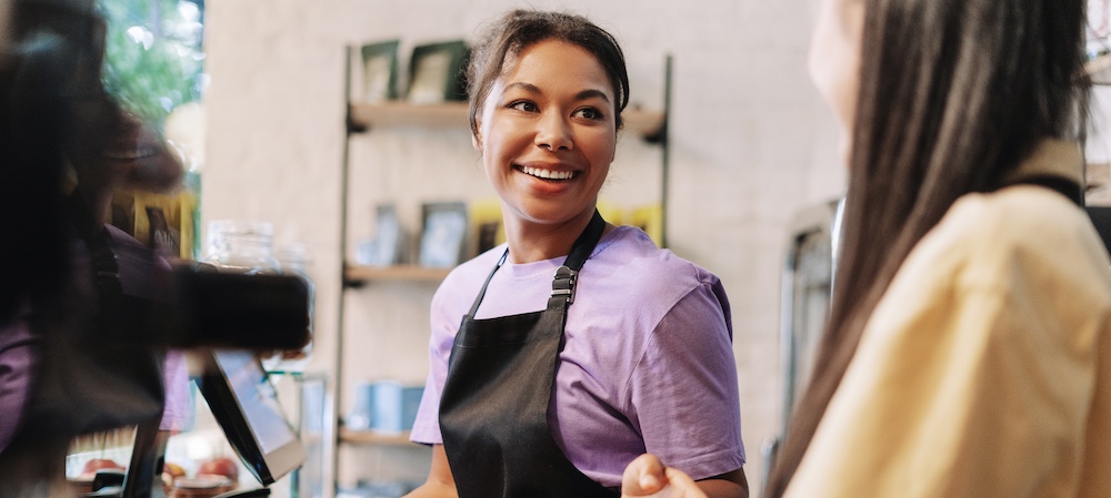 Two People Working Behind Counter with Aprons On