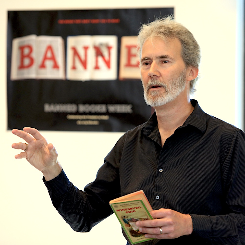 MPC English Teacher Henry Marchand Speaking and Holding Book at Banned Books Week Event