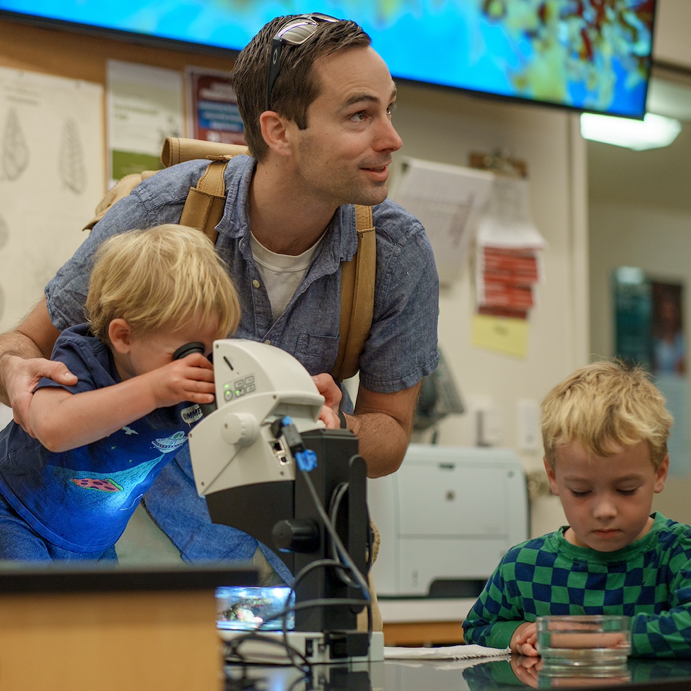 Man with his Children Looking at a Microscope and a Petrie Dish