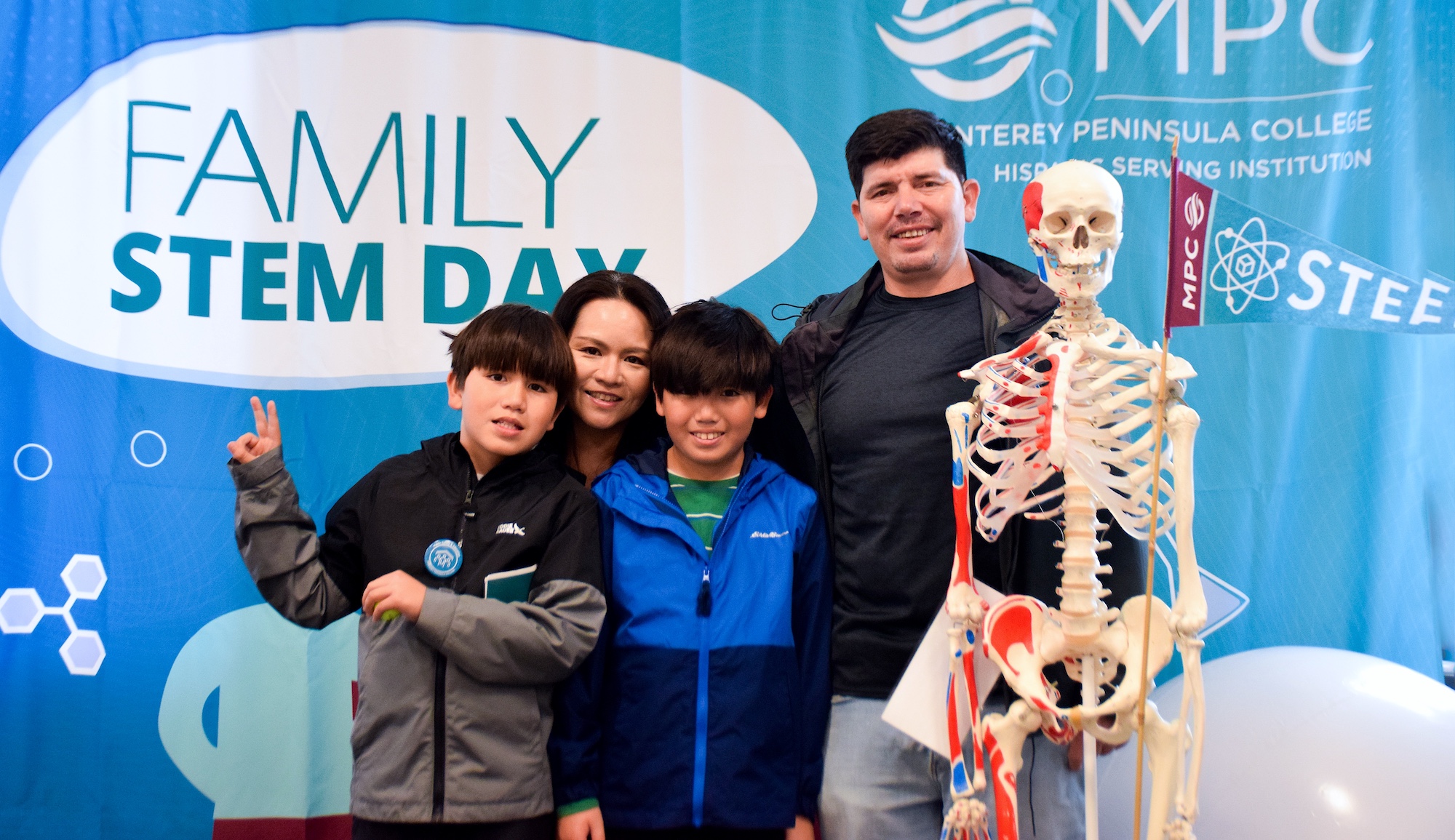 family posing for photo in front of family stem day backdrop