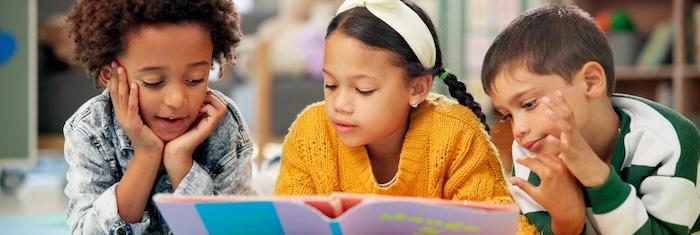 Three children reading book together