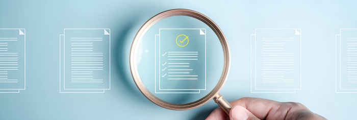 person holding magnifying glasses over graphic of resume