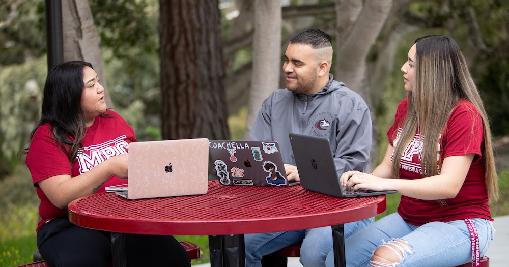 Three Students Discussing & Doing Work on Laptops