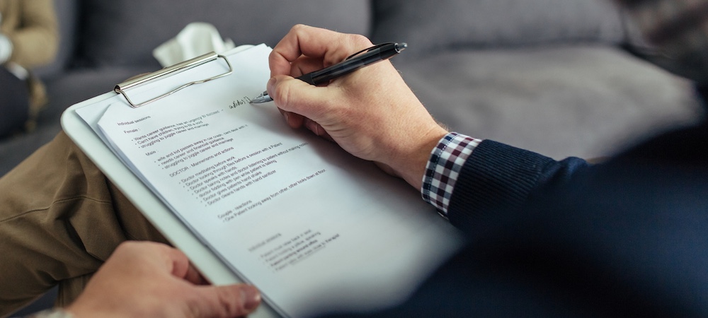 Therapist writing notes down on clipboard